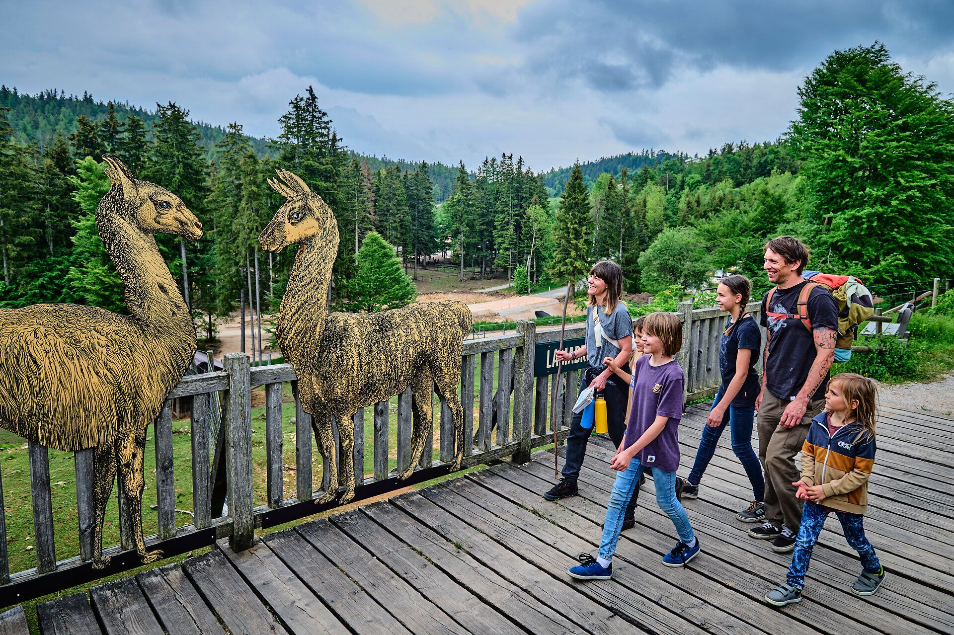 Eine Familie genießt einen unvergesslichen Tag in der Natur, während sie an einem Holzgeländer entlang spaziert. Die beeindruckende Kulisse der umliegenden Wälder und die kunstvollen Darstellungen von Tieren verleihen der Szenerie eine magische Atmosphäre. Hier wird die Schönheit der Natur in vollen Zügen erlebt.