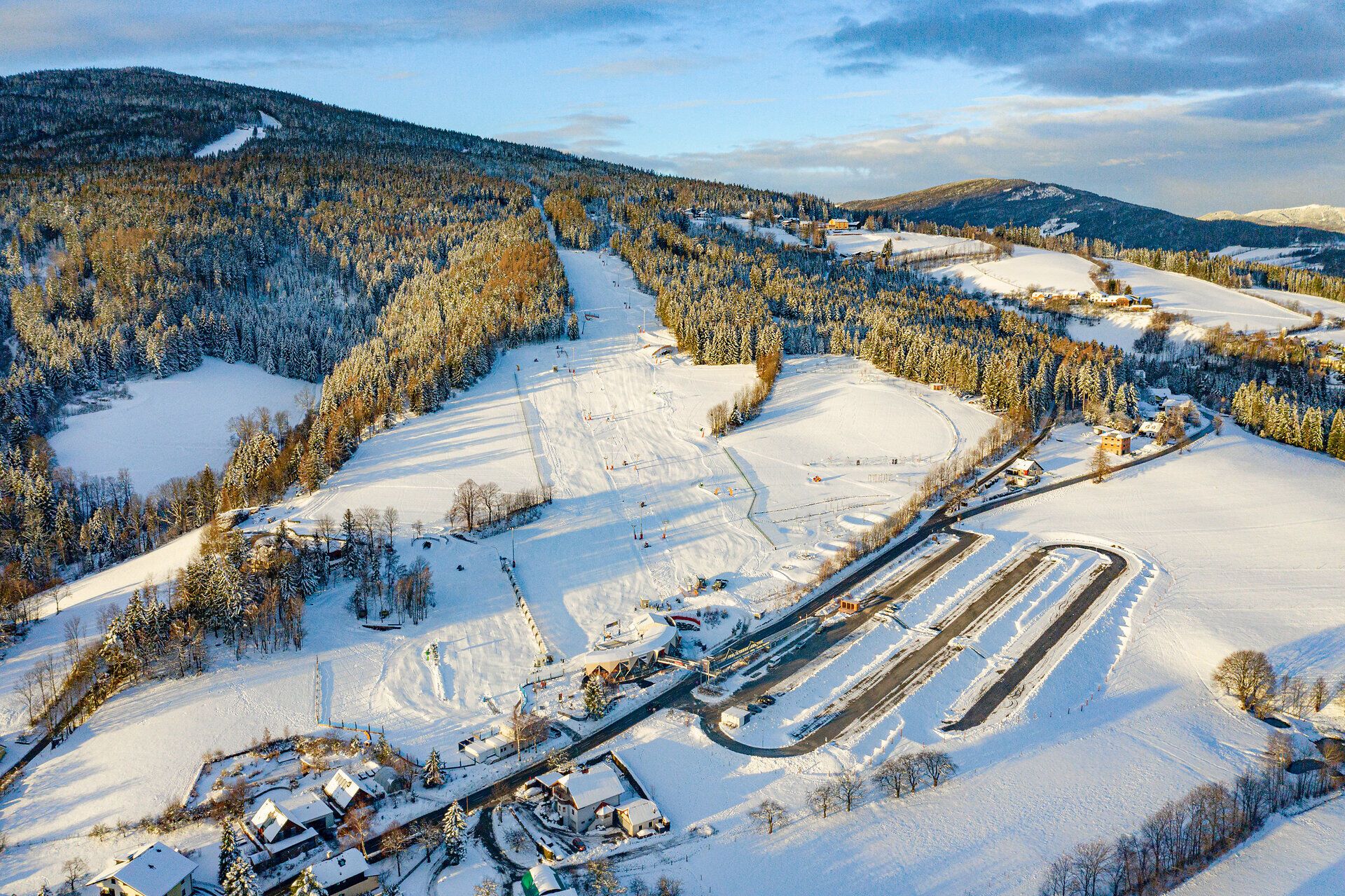 Luftaufnahme des verschneiten Kinderskilands der Wexl Arena mit Skipisten und Förderbändern