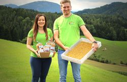 Ein Mann und eine Frau mit grünen T-Shirts stehen auf einer grünen Wiese und halten Nudelprodukte.