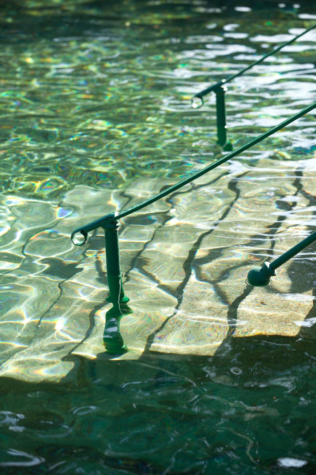 Close-up of a railing in a thermal bath with clear, greenish water.