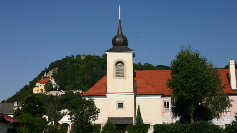 Pfarrhof Pitten mit Kirche und Hügel im Hintergrund.