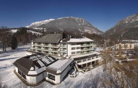 Parkhotel Hirschwang im Winter mit schneebedeckten Bergen im Hintergrund.