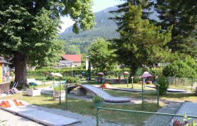 Minigolfplatz in Payerbach mit Bäumen und Bergen im Hintergrund.