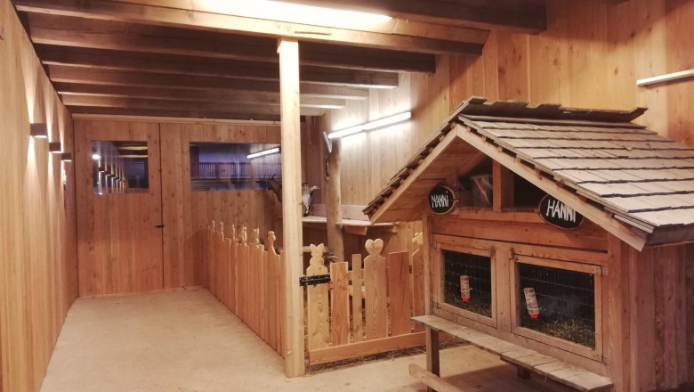 Innenansicht eines Ziegenstalls aus Holz mit Ziegengehege und kleinem H&auml;uschen.