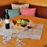 A table with wine bottle, wine glasses, fruit bowl and playing cards.