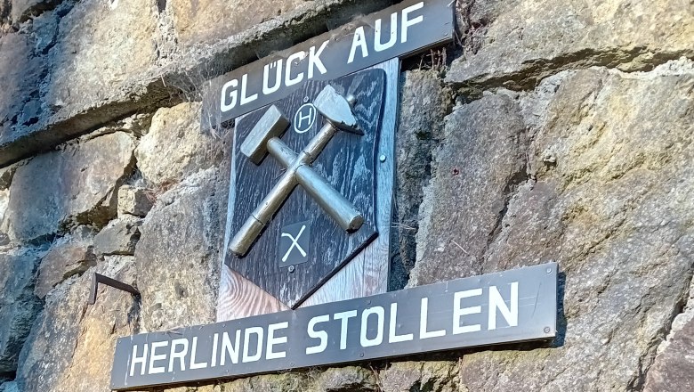Eingang zum Herlinde Stollen mit Bergbauzeichen und Schriftzug 'Glück Auf'.