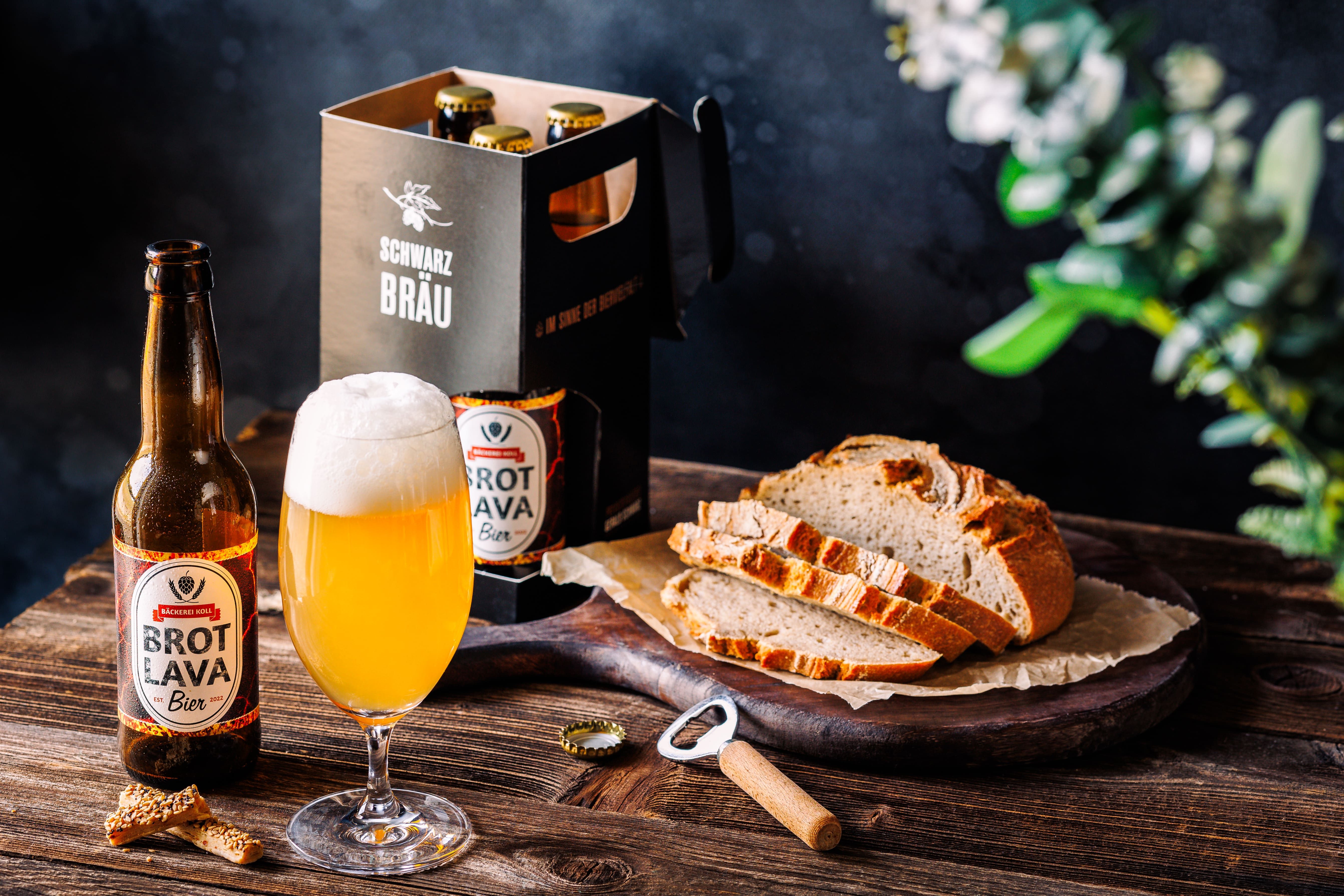 Ein Glas Bier und eine Flasche Brot Lava-Bier neben geschnittenem Brot auf einem Holztisch.