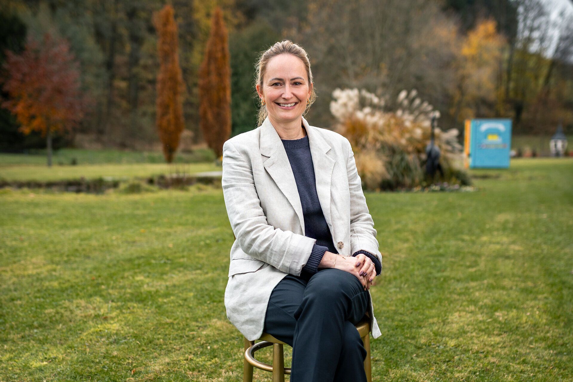 Tessa Erker-Tegetthoff, intendantin des Fabelhaft Festivals, sitzt auf einem goldenen Sessel auf einer grünen Wiese.