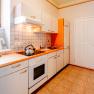 Bright kitchen with stove, sink and coffee machine.