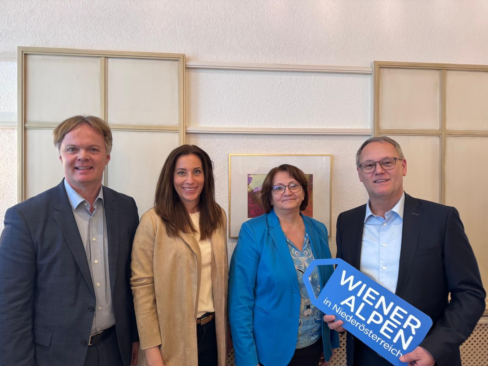 Vier Personen stehen nebeneinander und halten ein Logoschild in den Händen.