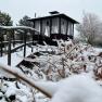 Verschneiter Zen-Garten mit Holzbrücke und Pavillon im Hintergrund.
