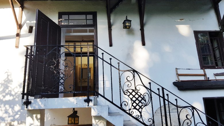 Eingangsbereich eines Hauses mit Treppe und schmiedeeisernem Gel&auml;nder.