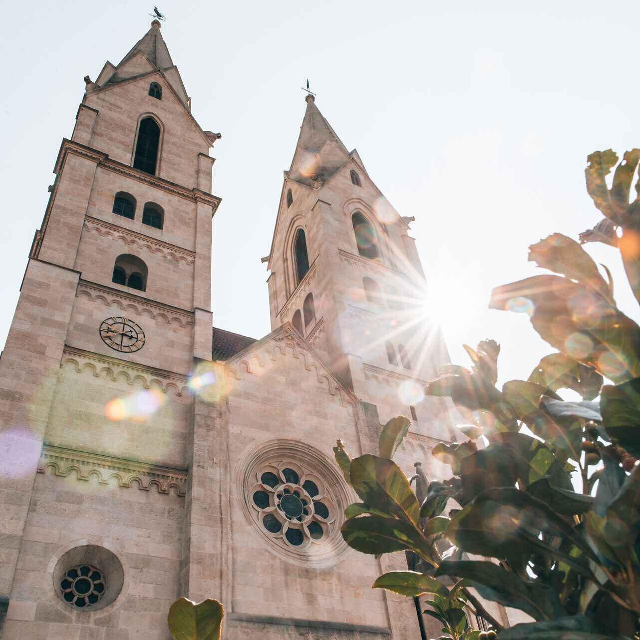 Die majestätischen Türme der Kirche ragen in den strahlend blauen Himmel und fangen das Licht der Sonne ein. Umgeben von üppigem Grün, strahlt dieser Ort eine friedliche Atmosphäre aus, die zum Verweilen einlädt. Hier vereinen sich Geschichte und Natur in harmonischer Weise.