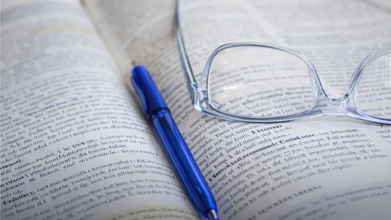 Kugelschreiber und Brille liegen auf einem offenen Buch