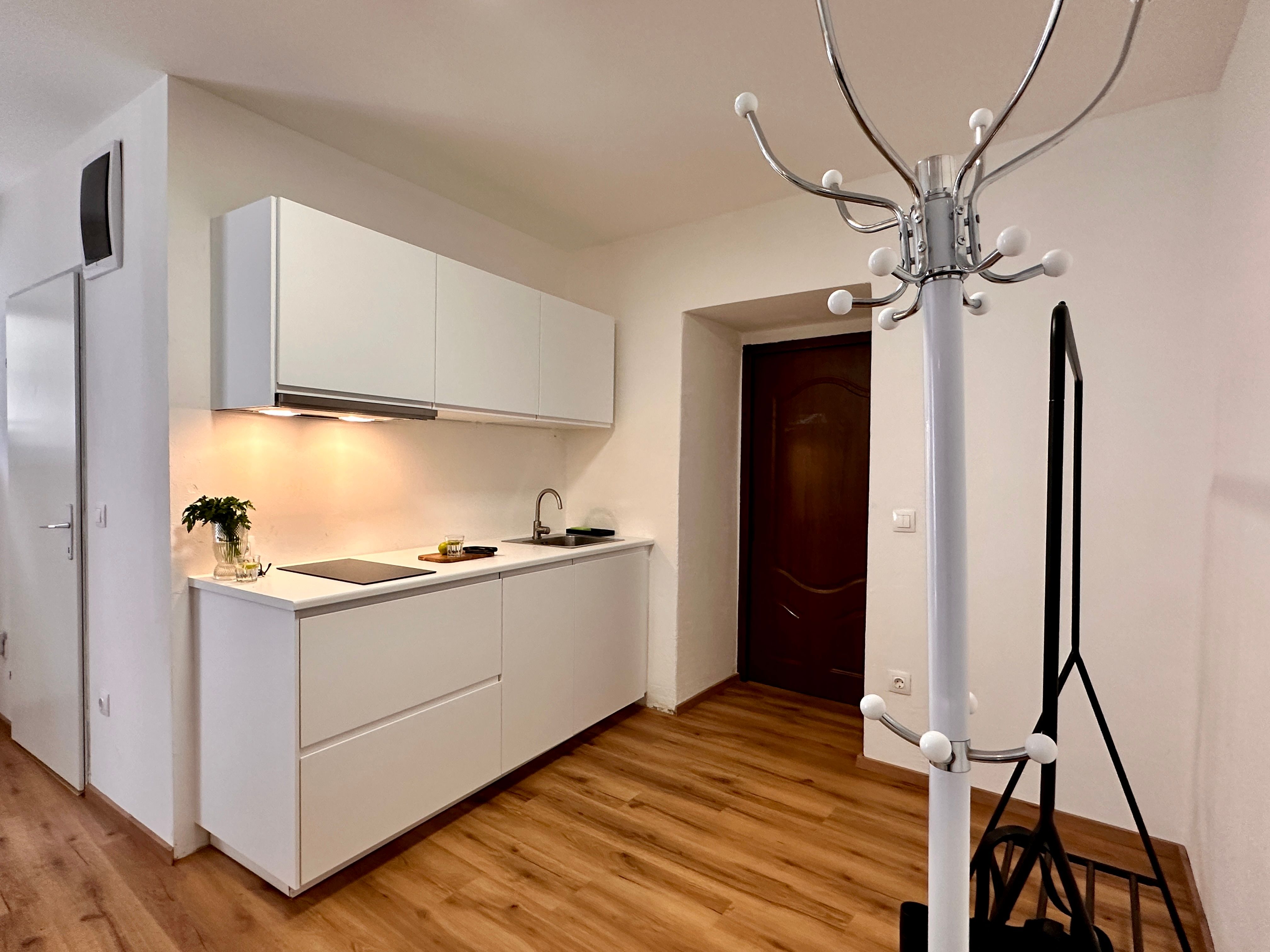 Moderne Küche mit weißen Schränken und Holzfußboden.