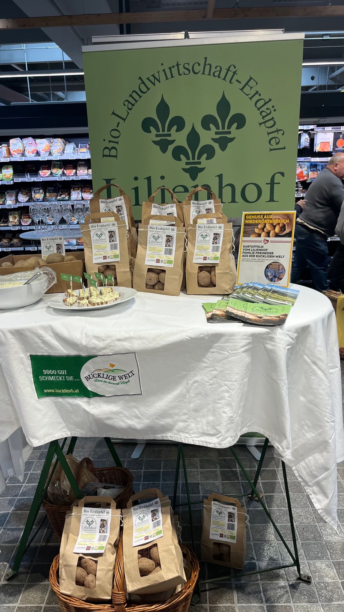 Ein Stand mit Kartoffeln, regionalen Produkten und Flyern in einem Supermarkt.