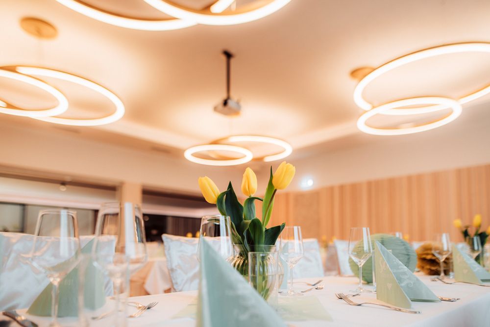 Eleganter Speisesaal mit moderner Beleuchtung und Tischdekoration mit gelben Tulpen.
