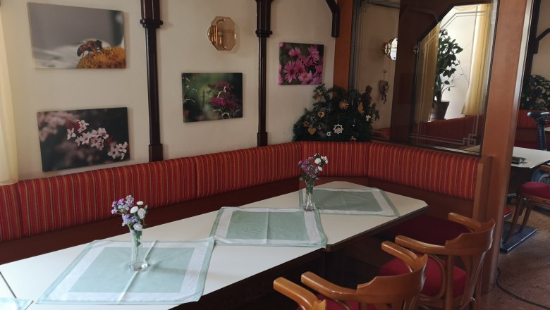Dining area with table, chairs and flower vases, decorated with flower pictures on the wall.