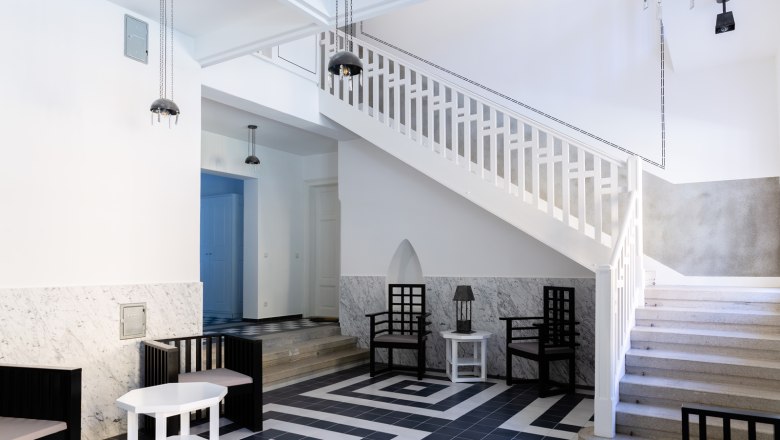 Moderner Eingangsbereich mit Treppe, schwarz-wei&szlig;en Fliesen und minimalistischen M&ouml;beln.