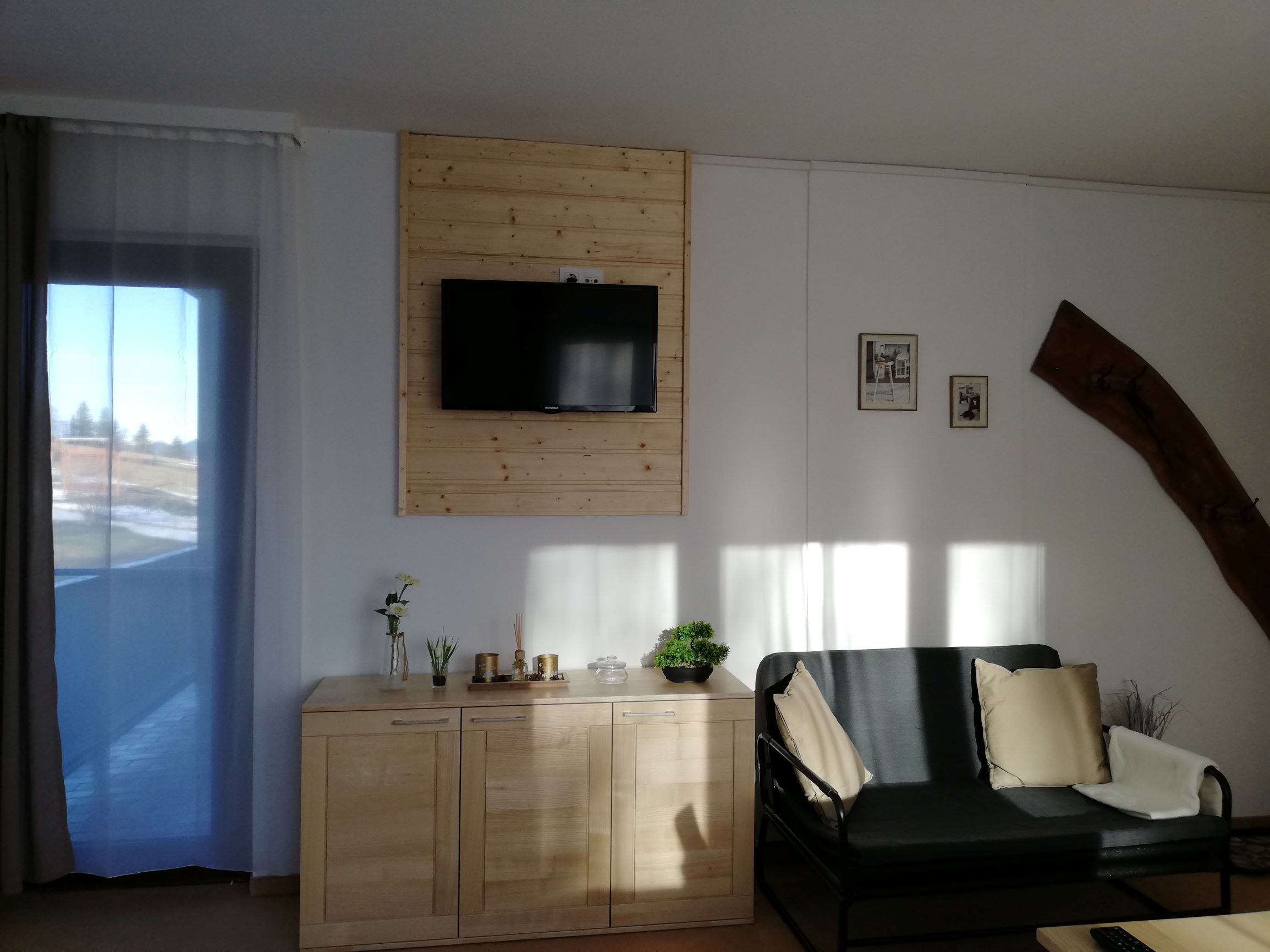 Wohnzimmer mit Sofa, Fernseher, Sideboard und Dekorationen.