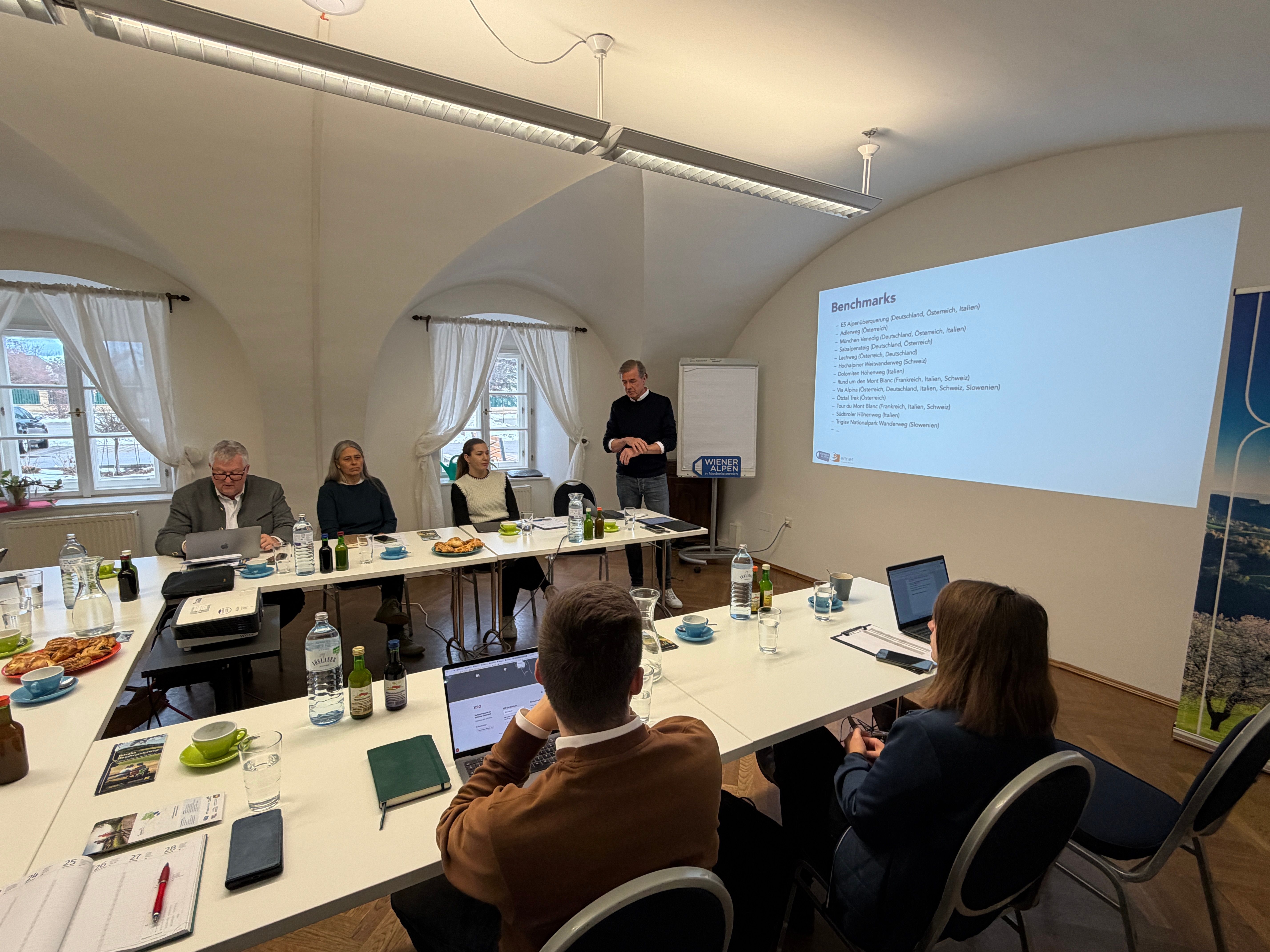 Mehrere Workshop Teilnehmer sitzen an Tischen, während ein Mann einen Vortrag hält.