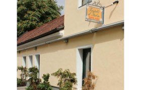 Au&szlig;enansicht eines gelben Geb&auml;udes mit einem Schild "Fratelli d'Italia Caff&egrave;-Pizza" und Pflanzen vor der Fassade.