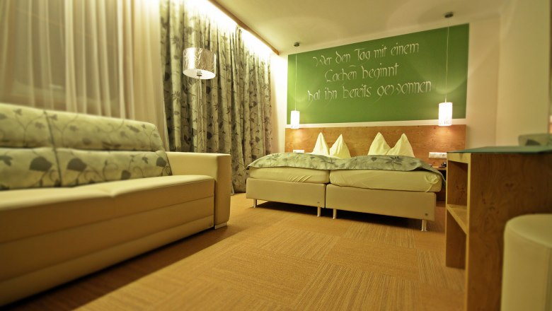 Cozy guest room with double bed, sofa and decorative curtains.