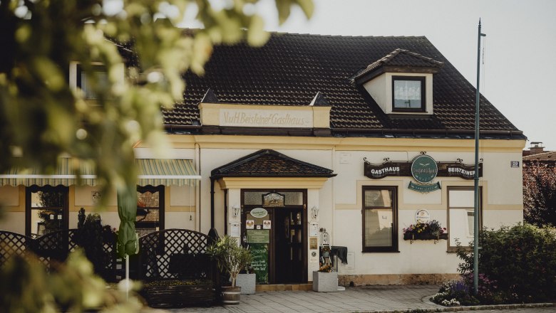Traditional inn with signs and plants in the foreground.