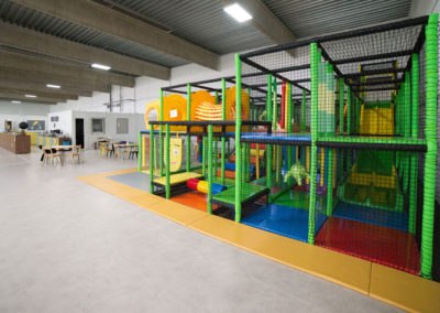 Innenansicht eines Indoor-Spielplatzes mit Klettergerüst und bunten Spielbereichen.