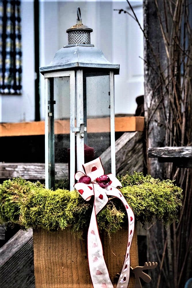 Laterne mit Moos und Schleife dekoriert.
