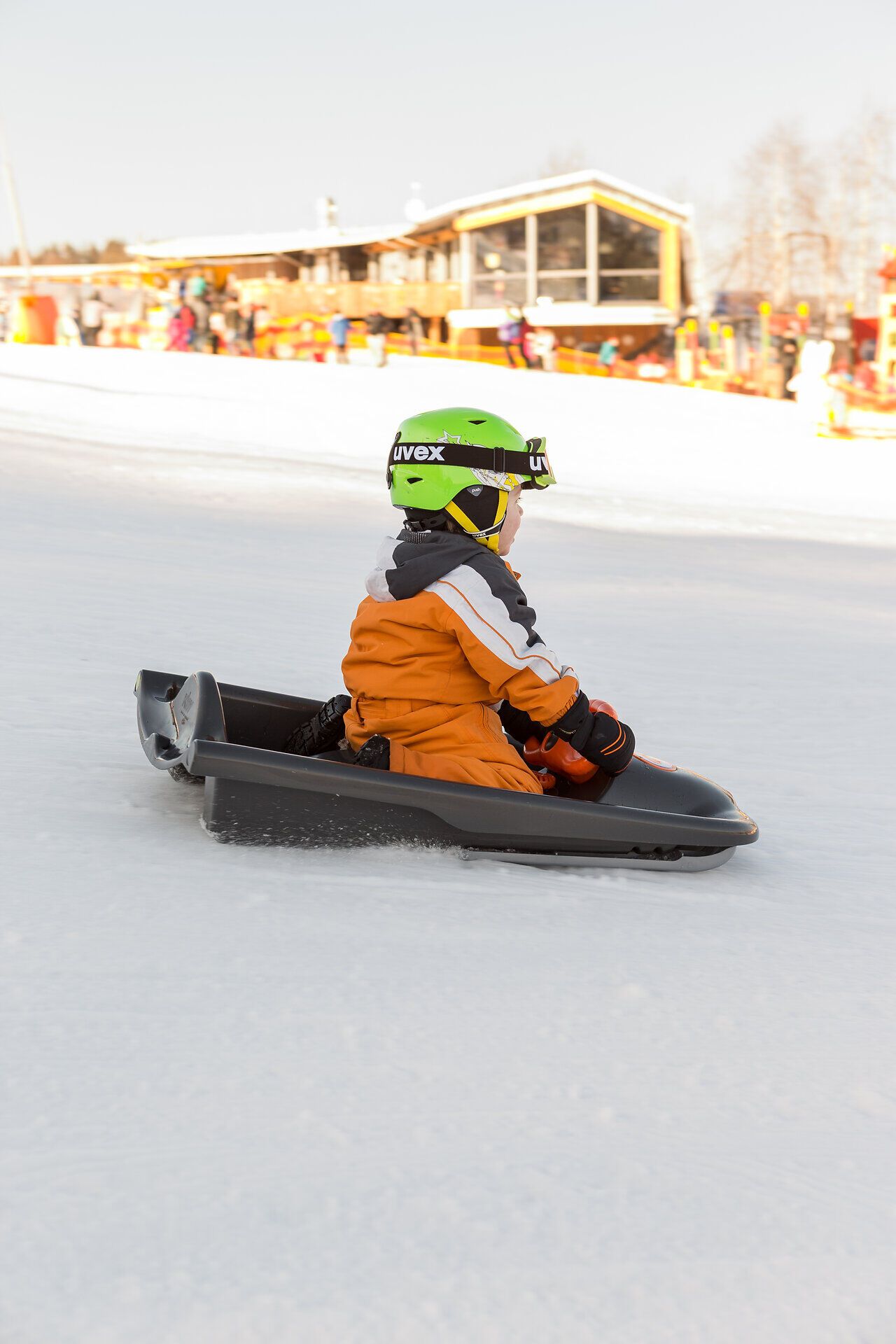 Ein fröhliches Kind saust mit einem Schlitten über die schneebedeckte Piste und genießt den Winterspaß in vollen Zügen. Die strahlende Sonne und die frische Bergluft schaffen eine unvergessliche Atmosphäre für kleine Abenteurer.