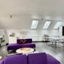Modernes Loft mit violetten Sofas, Esstisch und Küchenzeile unter Dachfenstern.