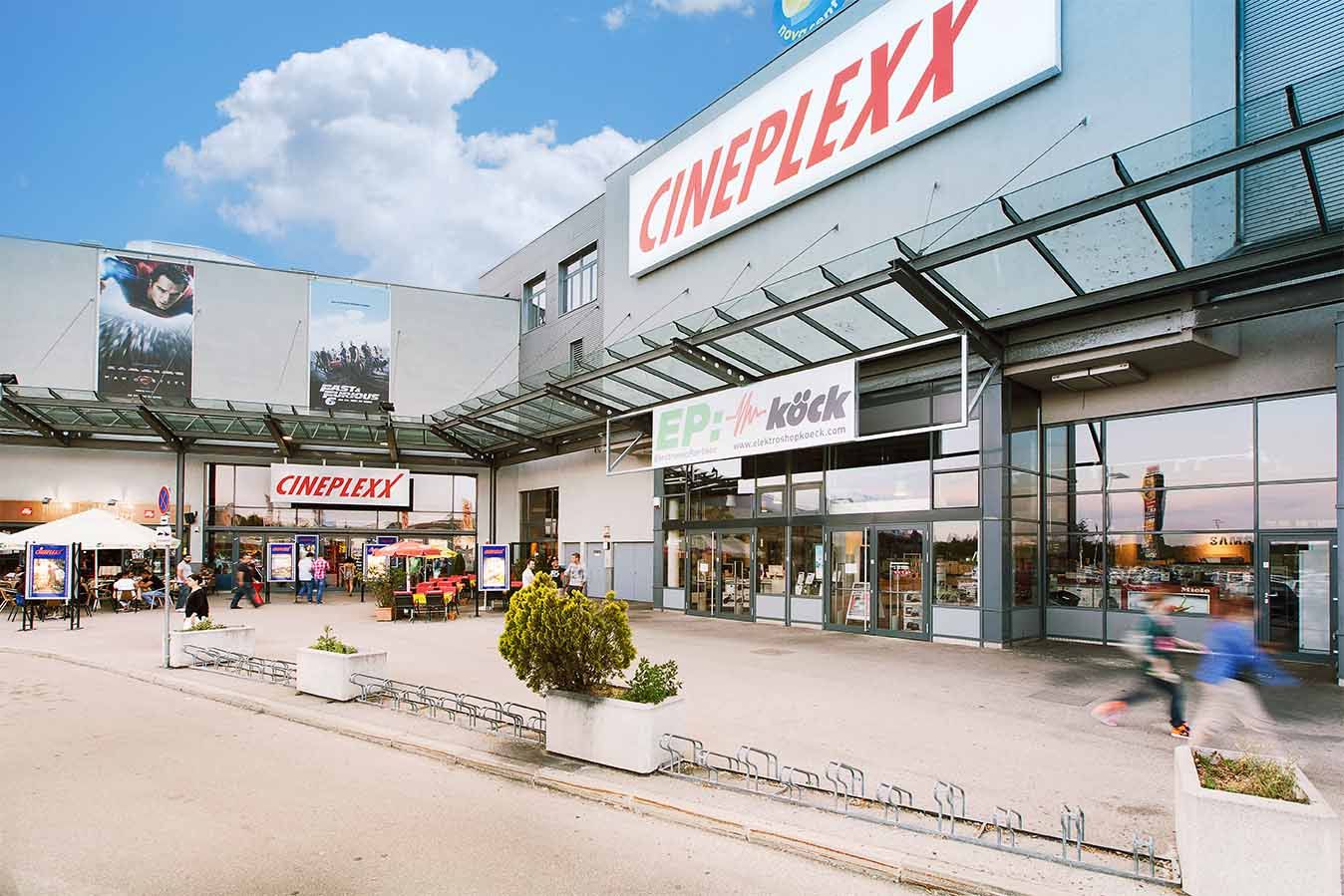Eingang des Cineplexx Kinos in Wiener Neustadt mit Glasdach und Werbeplakaten.