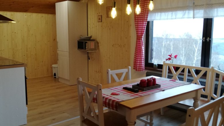 Gemütliches Dachgeschoss-Apartment mit Holzwänden, Esstisch und Hängelampen.