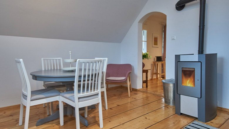 Gemütliches Wohnzimmer mit Esstisch, Stühlen, Sessel und Kamin.