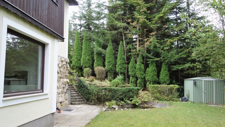 Garten mit Rasen, Bäumen und einem Schuppen.