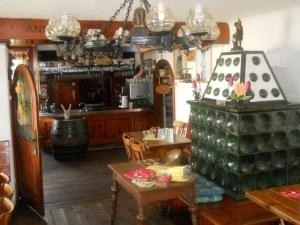 Gemütliches Gasthaus mit rustikaler Einrichtung, Holzmöbeln und einem grünen Kachelofen.