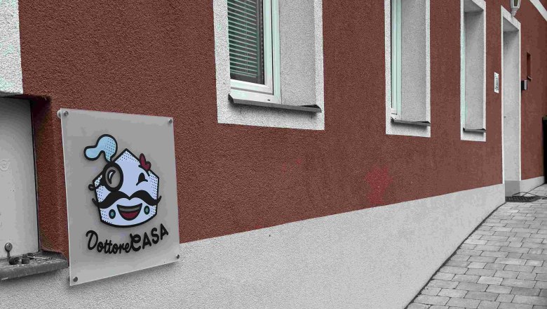 Au&szlig;enansicht eines Geb&auml;udes mit roter Fassade und einem Schild mit der Aufschrift 'Dottore Casa'.