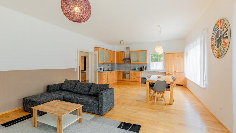 Küche und Wohnbereich, © Wiener Alpen / Christian Kremsl Offener Wohnbereich mit Küche, Esstisch und Sofa.