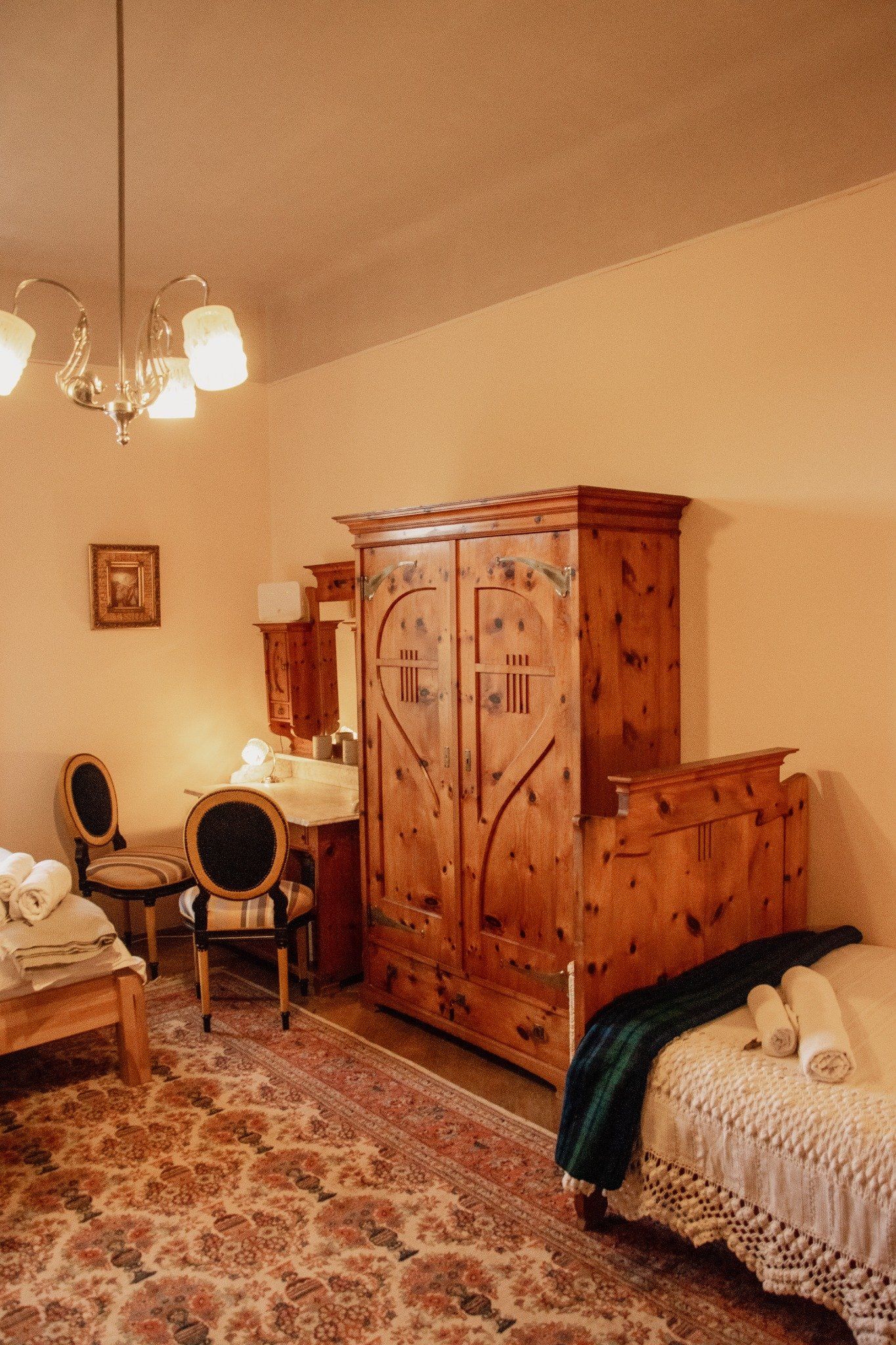 Ein gemütliches Zimmer mit Holzmöbeln, einem Teppich und einem Bett mit gefalteten Handtüchern.