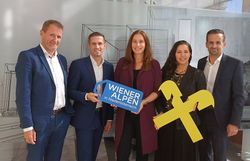Fünf Personen der Wiener Alpen in Niederösterreich & Raiffeisenbank Region Wiener Alpen stehen nebeneinander und halten ein Wiener Alpen-Logo Schild sowie ein Raiffeisenbank-Logo Schild in den Händen. 