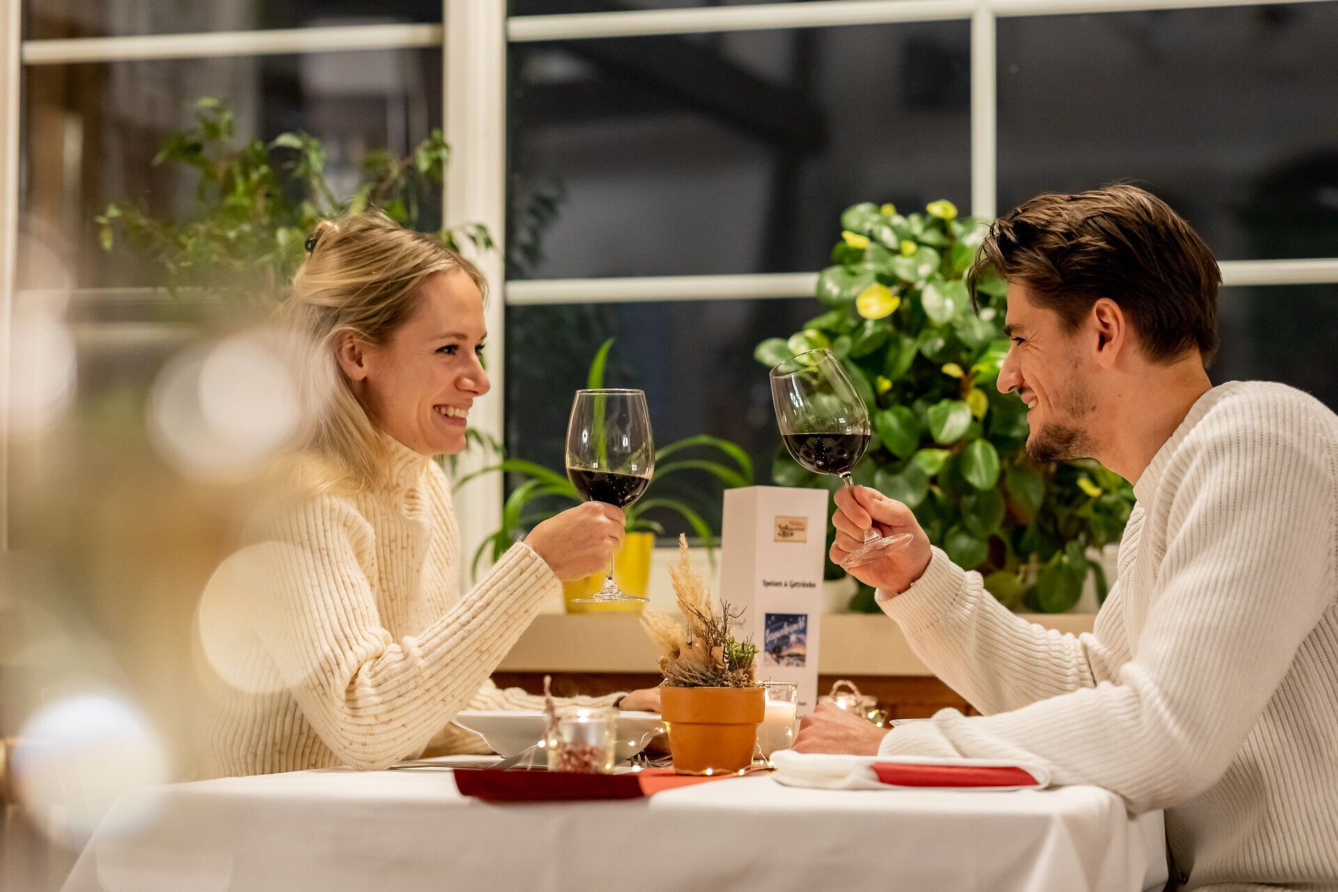 Paar sitzt sich in gemütlichem Raxalm-Berggasthof gegenüber und isst gemeinsam bei Kerzenlicht.