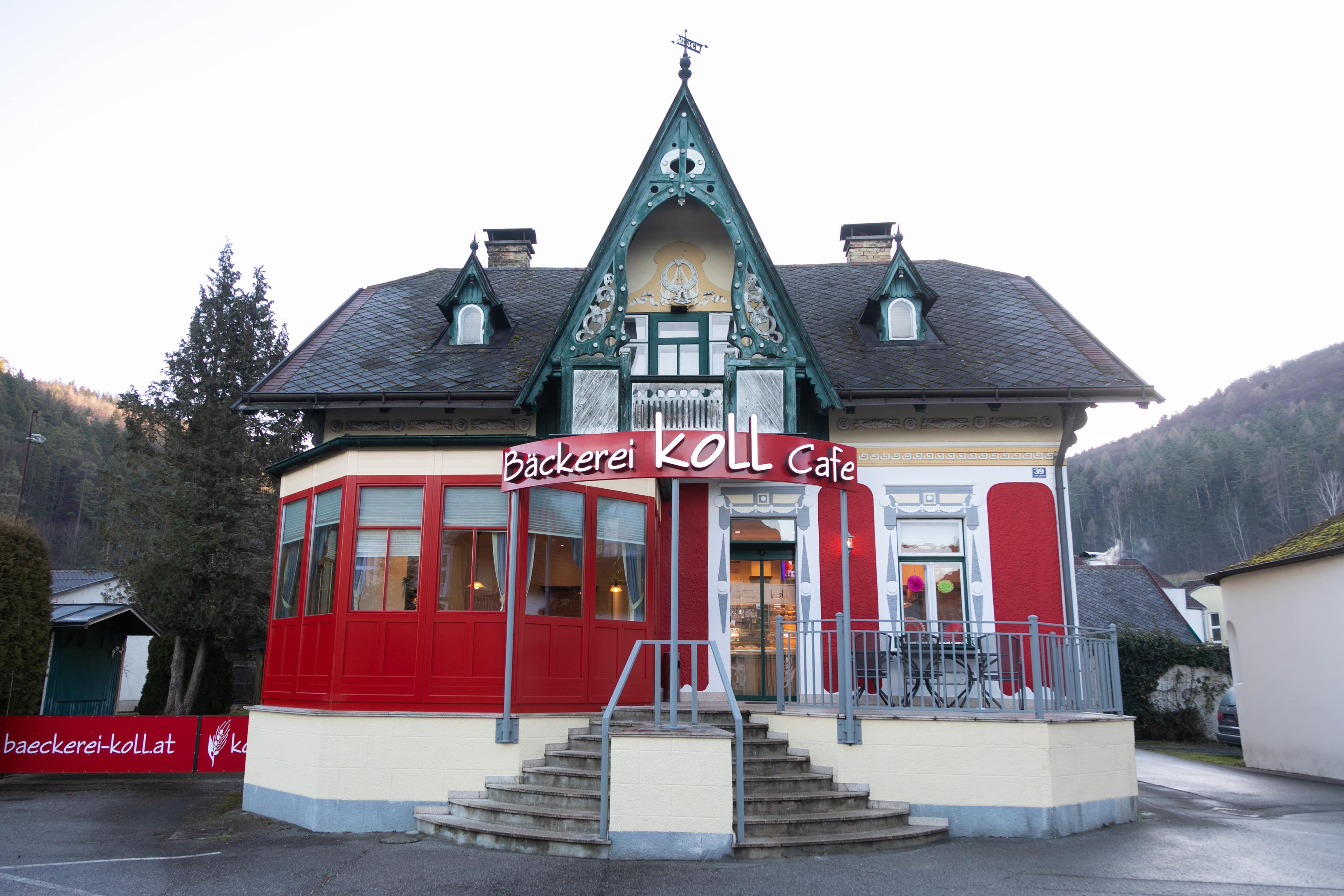 Bäckerei Koll Café in einem historischen Gebäude mit roter Fassade und dekorativem Giebel.