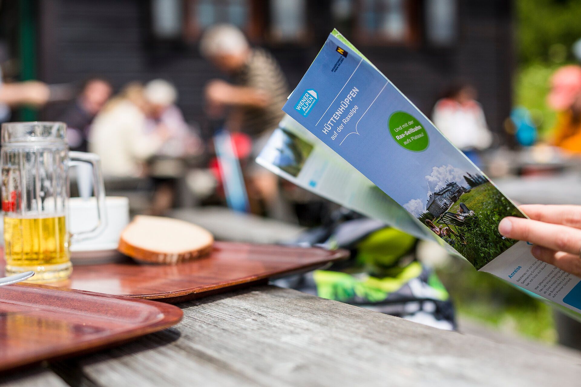 Ein erfrischendes Bier und eine informative Broschüre laden dazu ein, die atemberaubenden Wanderwege der Region zu erkunden. Umgeben von der malerischen Kulisse der Wiener Alpen, genießen die Besucher die Ruhe und Schönheit der Natur. Hier wird der Sommer in den Bergen zum unvergesslichen Erlebnis.