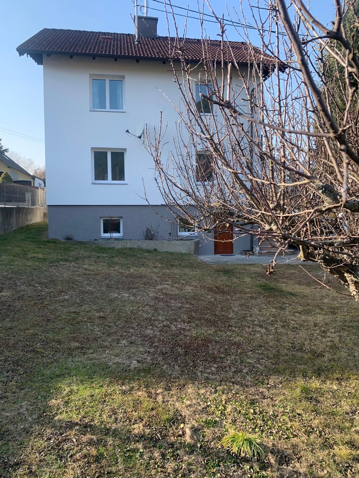 Außenansicht eines weißen Hauses mit rotem Dach und Garten.