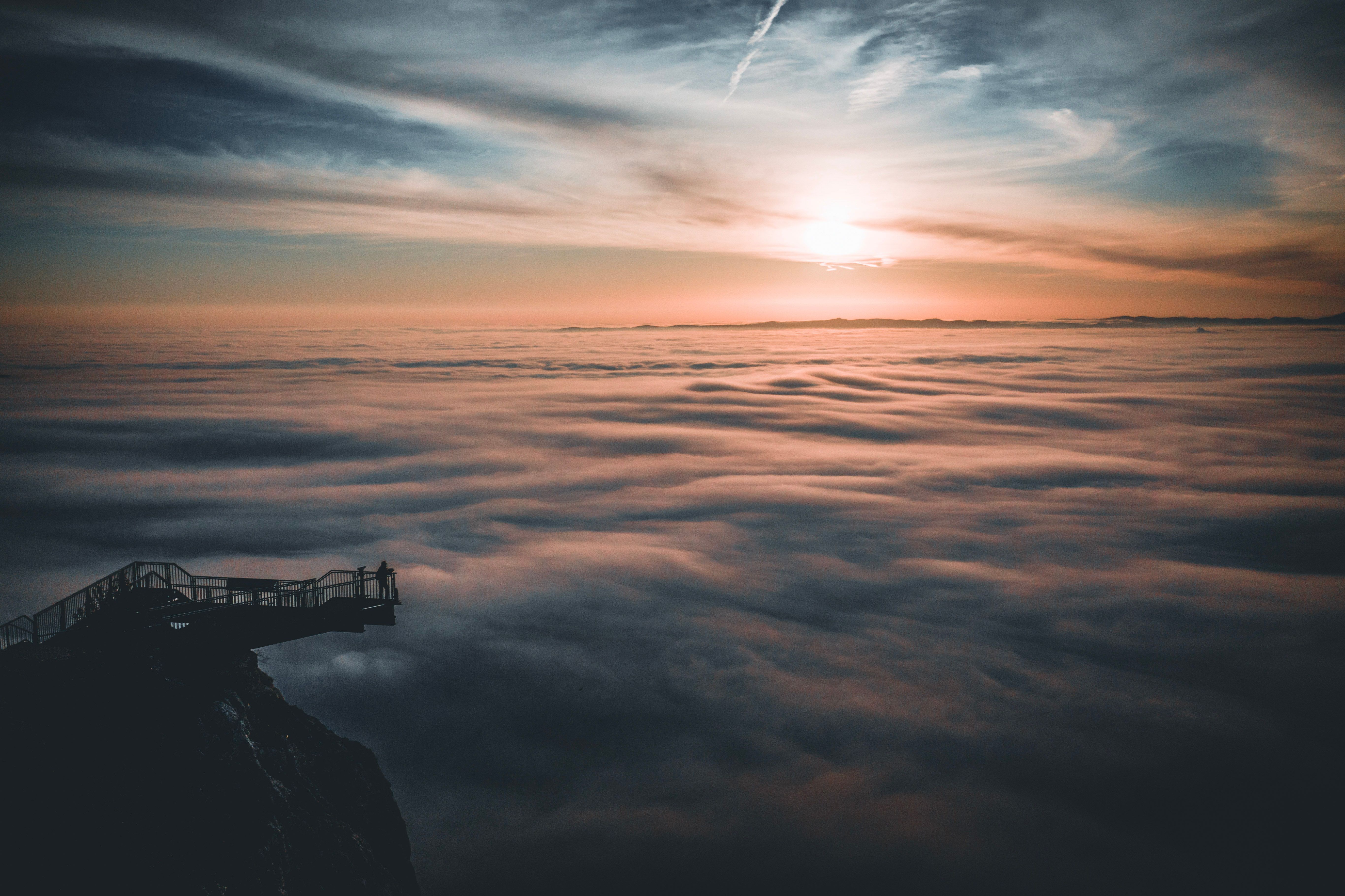 Aussichtsplattform über der Nebeldecke mit Sonnenuntergang am Horizont