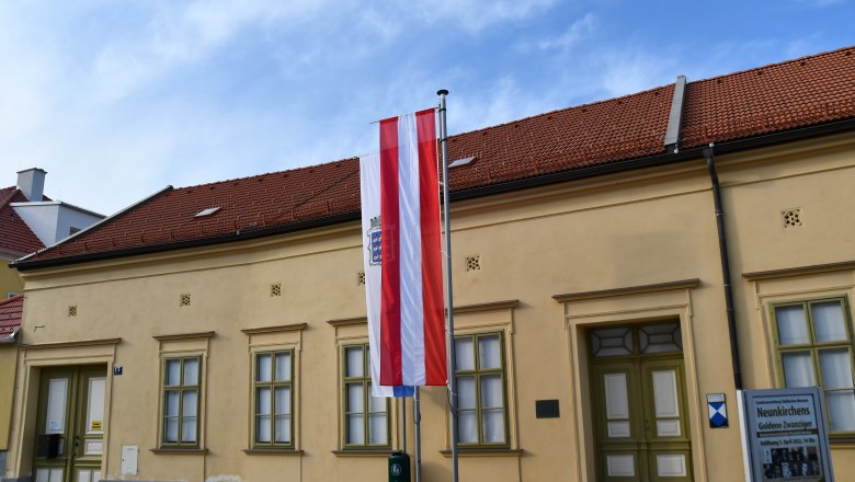 Exterior view of the Neunkirchen Museum with Austrian flag and information sign.