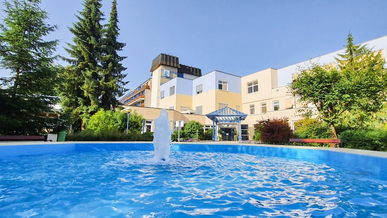 Entrance area of the K&ouml;nigsberg health resort with fountain and trees.