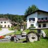 A rural guest house with flowers and an old millstone in the foreground.