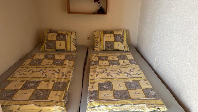 Zwei Einzelbetten mit gemusterten Bettdecken in einem kleinen Zimmer.